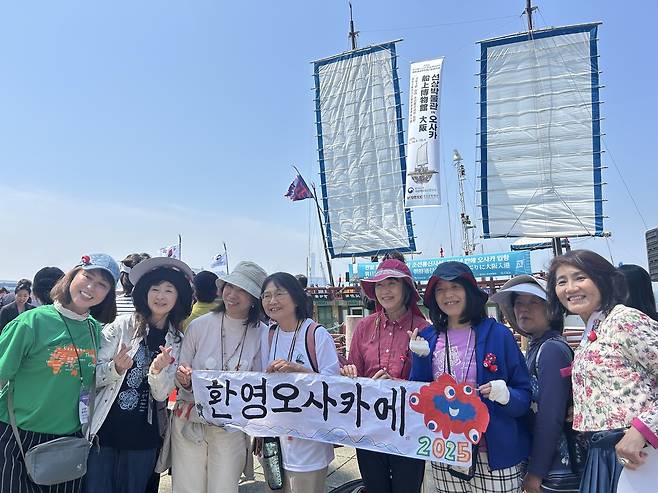 "환영합니다" (오사카=연합뉴스) 김예나 기자 = 13일 일본 오사카항 ATC 부두에서 열린 조선통신사선 재현선 입항 항해식에서 일본 시민들이 '환영, 오사카에'라고 적힌 현수막을 들고 있다. 2025.5.13
yes@yna.co.kr