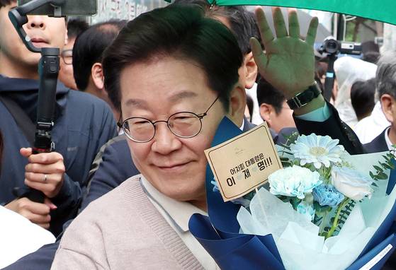 이재명 더불어민주당 대선후보가 9일 경북 칠곡군 석적읍 인근에서 한 지지자로부터 꽃다발을 받아 들고 있다. 뉴시스