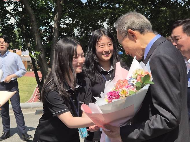 이명박 전 대통령이 동지여고 학생에게 환영의 꽃을 받고 기뻐하고 있다.