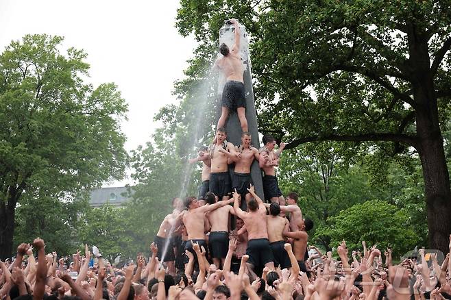 미국 해군사관학교에서 사관생도들이 14일(현지시간) 미국 메릴랜드 주 아나폴리스 미 해군 사관학교에서 '딕시 컵'을 떨어뜨리기 위해 인간 피라미드를 만들어 헌던 기념물 꼭대기에 오르고 있다. ⓒ AFP=뉴스1