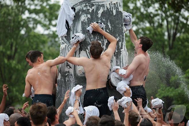 미국 해군사관학교에서 사관생도들이 14일(현지시간) 미국 메릴랜드 주 아나폴리스 미 해군 사관학교에서 '딕시 컵'을 떨어뜨리기 위해 인간 피라미드를 만들어 헌던 기념물 꼭대기에 오르고 있다. ⓒ AFP=뉴스1