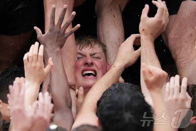 미국 해군사관학교에서 사관생도들이 14일(현지시간) 미국 메릴랜드 주 아나폴리스 미 해군 사관학교에서 '딕시 컵'을 떨어뜨리기 위해 인간 피라미드를 만들어 헌던 기념물 꼭대기에 오르고 있다. ⓒ AFP=뉴스1