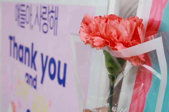 스승의날인 15일 서울 성동구 서울방송고에서 등교하는 학생들을 맞이하는 교사가 카네이션과 손팻말을 들고 있다. 연합뉴스