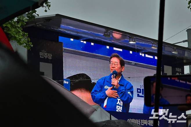 이재명 후보가 순천에서 장대비속에 유세하는 것을 우산을 든 시민들이 지켜보거나 촬영하고 있다. 고영호 기자