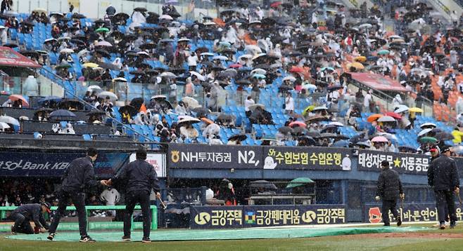 지난달 13일 서울 잠실야구장에서 열린 2025 프로야구 두산베어스와 LG트윈스의 경기가 우천으로 중단돼 구단 관계자가 방수포를 덮는 모습./사진=뉴시스