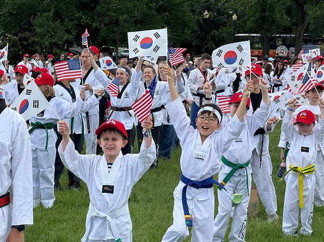 18일 미국 워싱턴 DC 백악관 맞은 편 잔디밭에서 열린 태권도 축제에서 현지 태권도 수련생들이 태극기와 성조기를 흔들고 있다. /박국희 특파원