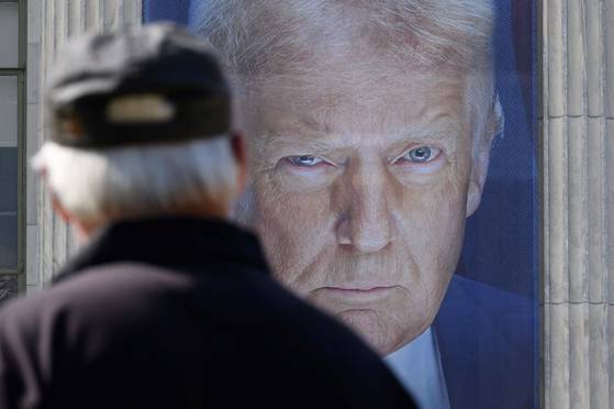 지난 16일 워싱턴DC에 있는 농무부 건물에 걸려 있는 도널드 트럼프 미국 대통령의 현수막을 한 행인이 바라보고 있다. 해당 현수막은 에이브러햄 링컨이 1862년 5월 15일에 설립한 농무부의 163주년을 기념하기 위해 게시됐다. AFP=연합뉴스