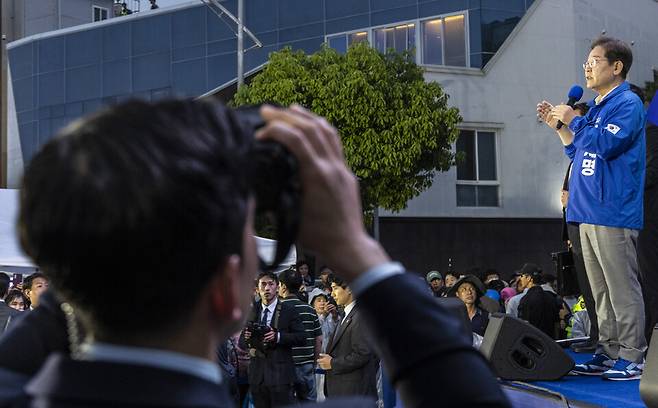 이재명 더불어민주당 대선 후보가 5월15일 전남 목포시 평화광장 원형상가 앞에서 유세를 하는 가운데, 경찰 경호 관계자가 유세차 아래에서 테러 위협에 대응하기 위해 특수 쌍안경을 이용해 근처 건물을 계속 지켜보고 있다. ⓒ연합뉴스