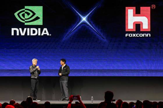 젠슨 황 엔비디아 최고경영자(CEO)가 20일 대만 타이베이에서 열린 컴퓨텍스2025의 폭스콘 류양웨이 CEO 기조연설 무대에 깜짝 등장하고 있다. AFP=연합뉴스