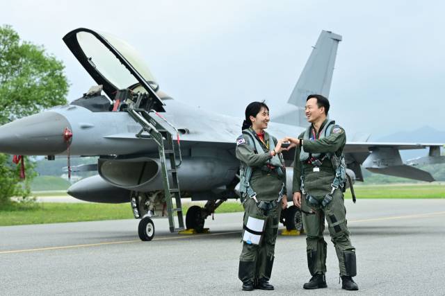 부부 사이인 윤해림(왼쪽) 소령과 강명진 소령이 전투기 앞에서 손하트를 만들어 보이고 있다. 사진 제공=공군