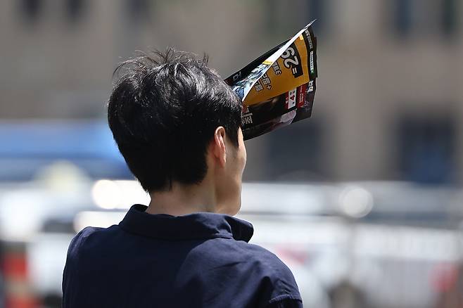 서울 종로구 광화문에서 한 시민이 전단지로 햇빛을 가리고 있다. /연합뉴스