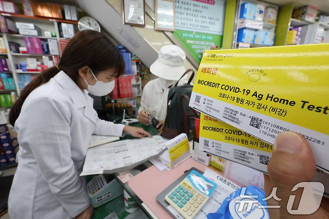 서울 종로구 새종로약국에서 약사가 코로나19 자가 키트를 구매하는 고객에게 사용법을 알려주고 있다. /뉴스1 ⓒ News1 신웅수 기자
