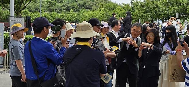 김상욱 국회의원이 노무현 전 대통령 묘역 앞에서 참배객들에게 둘러싸여 기념사진을 찍고 있다.