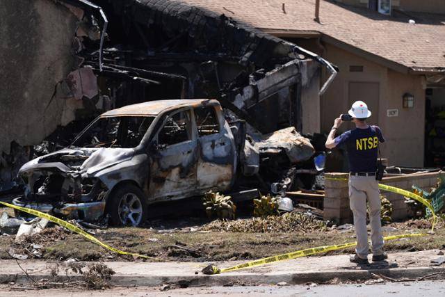 미국 연방교통안전위원회(NTSB) 직원이 22일 소형 비행기가 추락한 미국 캘리포니아주 샌디에이고의 군부대 주택 단지에서 파손된 차량 사진을 찍고 있다. 샌디에이고=AP 연합뉴스