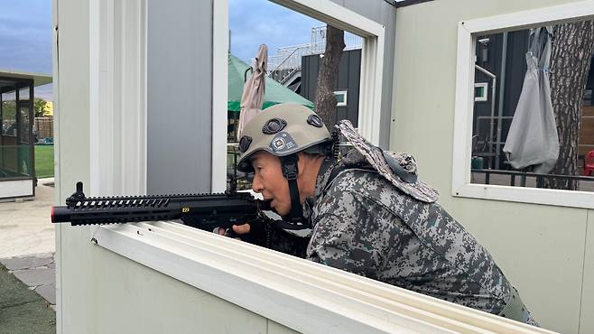 24일 오후 시니어 아미 소속 '시니어 일일병사'가 컨테이너 박스에 몸을 숨기고 적진을 향해 총구를 겨누고 있다. 이날 시가전 모의 훈련에서는 드론 4대가 투입됐다./김도균 기자