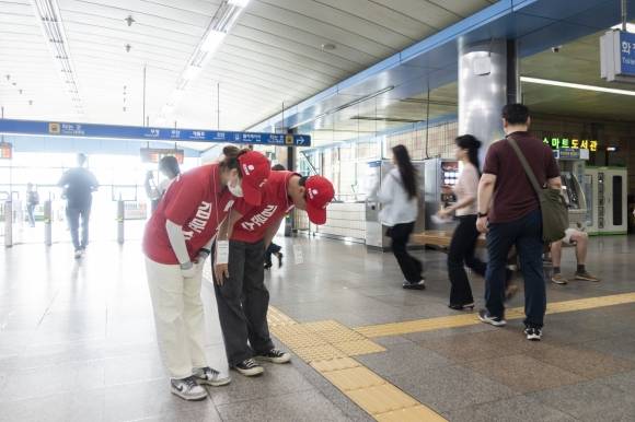 이은주(왼쪽)씨와 장세민씨가 21일 지하철 1호선 개봉역에서 출근길에 바쁜 시민들을 향해 인사하고 있다.