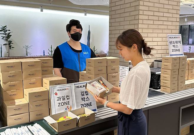 모델이 GS25의 밀박스25를 살펴보고 있다.