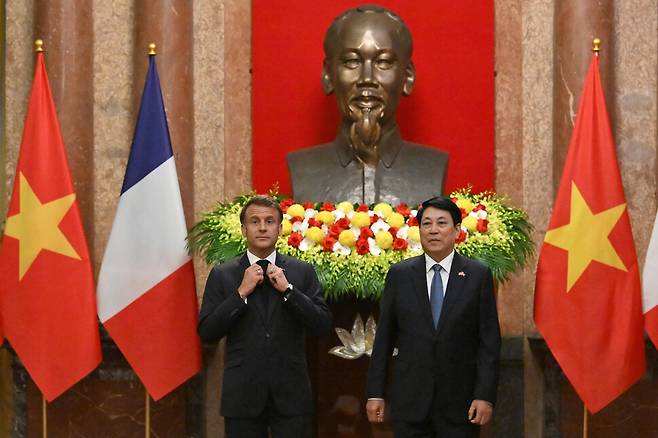 에마뉘엘 마크롱 프랑스 대통령이 26일 베트남 하노이 대통령궁에서 르엉끄엉 베트남 국가주석과 함께 호찌민 흉상 앞에 서 있다. 사진 AP