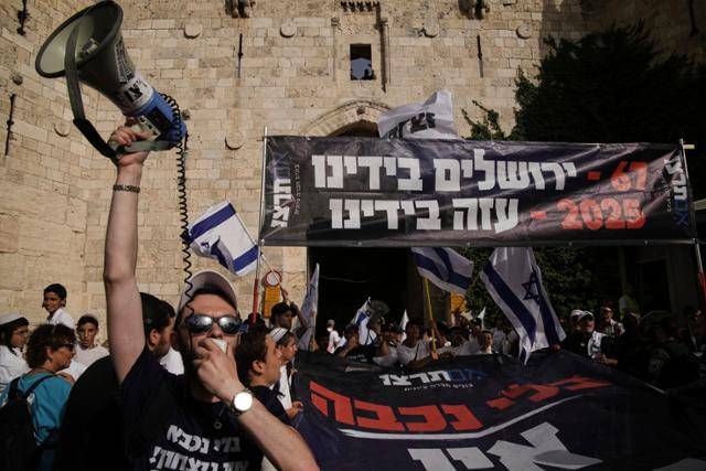 극우 성향 이스라엘인들이 26일 예루살렘 구시가지에서 벌어진 집회에서 히브리어로 '67년에는 예루살렘이 우리 손에, 2025년에는 가자지구가 우리 손에'라고 적힌 현수막을 들고 시위를 벌이고 있다. 예루살렘=AP 연합뉴스