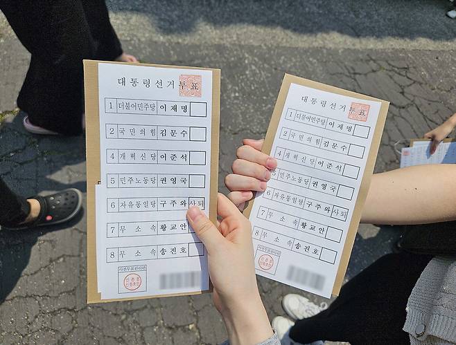 29일 오전 11시 25분쯤 구신촌동주민센터 사전투표소 밖에서 유권자들이 배부받은 투표용지를 들어 보이고 있다. 지혜진 기자