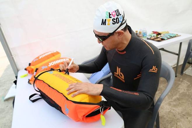 오세훈 서울시장이 30일 '쉬엄쉬엄 한강 3종 축제' 수영종목 출발에 앞서 안전부이에 '수영하기 너무 좋은 한강으로 오세요, 수질 환상적!' 문구를 쓰고 있다. 서울시