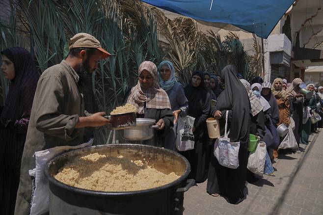 30일 가자지구에서 팔레스타인 여성이 음식을 배급받고 있다. AP연합뉴스