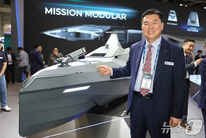 신용화 LIG넥스원 미래전장사업본부장 전무가 29일 부산 벡스코에서 전투용 무인수상정 '해검-X'를 배경으로 사진을 촬영한 모습. LIG넥스원은 전날 이곳에서 개막한 제14회 국제해양방위산업전(MADEX·마덱스)에서 전투용 무인수상정을 처음으로 공개했다. 2025.05.29/뉴스1 김성식 기자