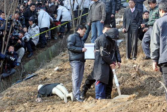 연쇄살인범 강호순이 2009년 1월 경기도 화성시 자안리 39번 국도 인근 현장검증에서 군포 노래방 도우미를 살해한 뒤 암매장하는 모습을 재연하고 있다. 중앙DB