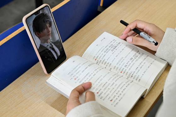 한 중국 여성이 대학 강의실에서 가상 캐릭터와 함께 책을 읽고 있다. AFP=연합뉴스