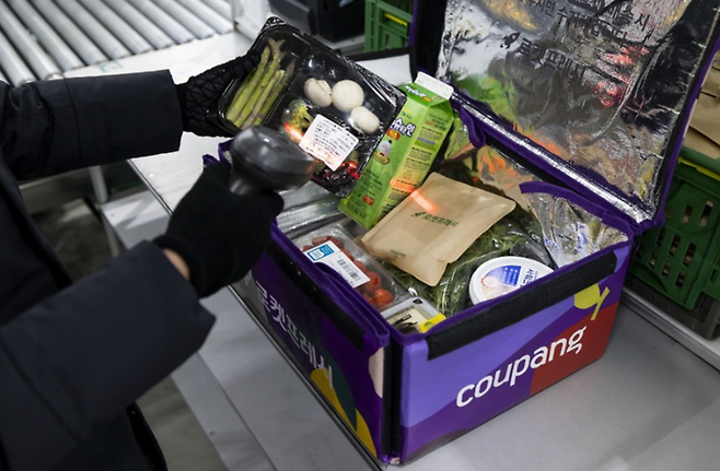 쿠팡 물류센터에서 작업자가 프레시백에 상품을 담고 있다.