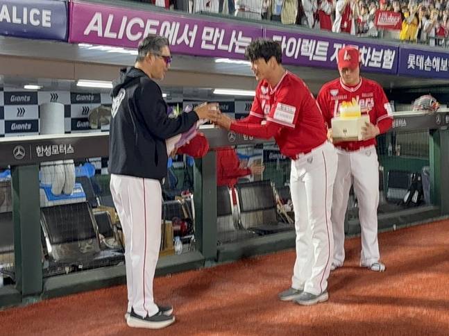 SSG 감독으로 100번쨰 승리를 수확한 이숭용 감독(왼쪽)에게 김광현이 기념구와 최정이 케이크를 선물하려고 하고 있다. /사진=SSG 랜더스