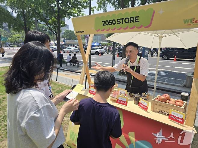 1일 정상훈 그린피스 선임 캠페이너가 2050년에는 구매하기 어렵거나 비쌀 것으로 예상되는 사과, 전복 등이 전시된 부스에서 시민에게 탄소중립에 대해 설명하고 있다. ⓒ 뉴스1 황덕현 기자