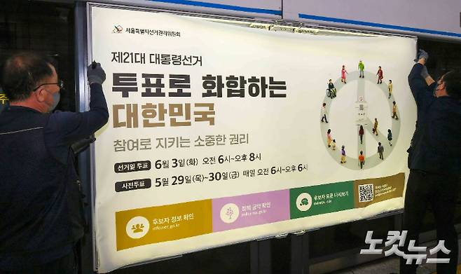 선관위 관계자들이 투표독려 홍보물을 게시하고 있다. 박종민 기자