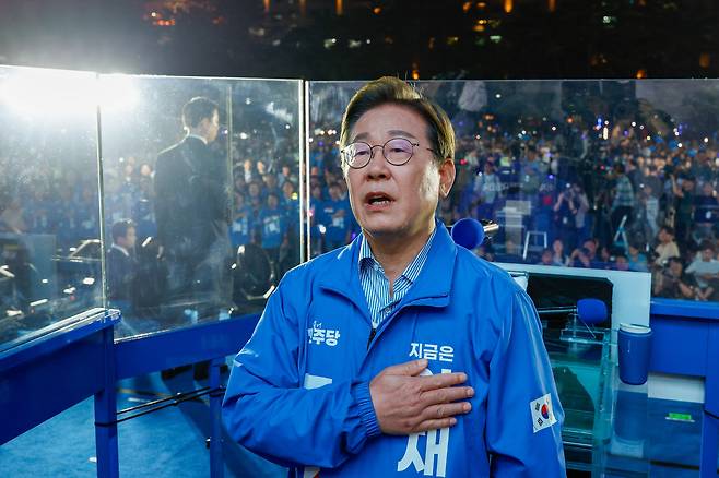 더불어민주당 이재명 대선 후보가 선거를 하루 앞둔 2일 서울 여의도공원 마지막 유세에서 연설을 마친 뒤 애국가를 부르며 국기에 경례하고 있다. /연합뉴스