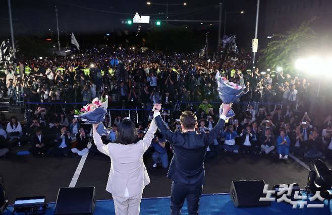 제21대 대통령 당선이 확실시되는 더불어민주당 이재명 대선 후보와 김혜경 여사가 4일 서울 여의도 국회 앞에 마련된 더불어민주당 국민 개표방송 행사에서 꽃다발을 받은 뒤 인사하고 있다. 류영주 기자