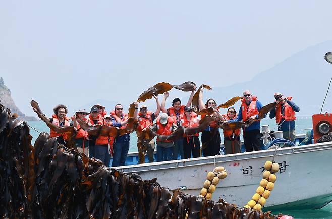 지난 2일 전남 완도군의 다시마 양식장을 찾은 세계자연기금(WWF) 관계자들이 배에서 기념촬영을 하고 있다. 완도군 제공