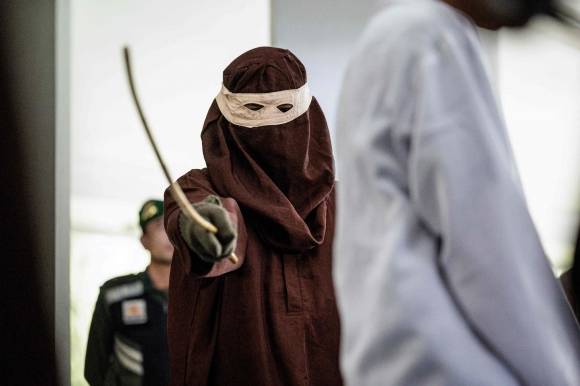 다른 남성과의 성관계로 유죄 판결을 받은 한 남성이 인도네시아 아체주의 주도인 반다아체에서 공개적으로 채찍질을 당하는 모습. 2025.2.27 AFP 연합뉴스