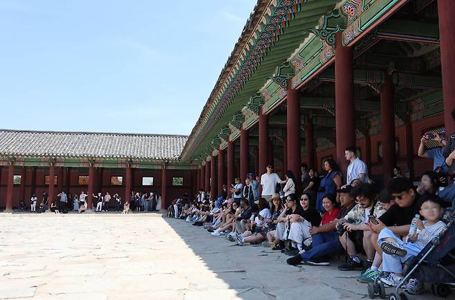 6일 오후 서울 종로구 경복궁을 찾은 관람객들이 햇빛을 피해 그늘에 모여 앉아 있다. 뉴스1