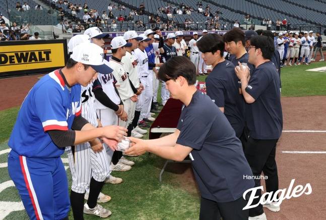 KBO 스카우트들(왼쪽 검은색 상의)이 지난 2일 대전 한화생명 볼파크에서 열린 2025 제3회 한화 이글스배 고교·대학 올스타전을 앞두고 대학 올스타 선수들에게 기념구를 전달하고 있다. /사진=한화 이글스 제공