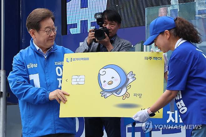 (파주=연합뉴스) 김주성 기자 = 더불어민주당 이재명 대선 후보가 20일 경기 파주시 금릉역 중앙광장에서 열린 유세에서 지역화폐 모형을 전달받고 있다. 2025.5.20 utzza@yna.co.kr 연합뉴스