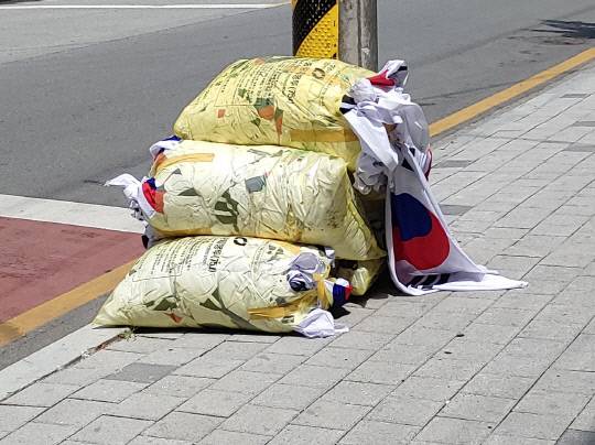 현충일인 지난 6일 충북 청주의 한 도로변에 다량의 태극기가 담긴 쓰레기 종량제 봉투 더미가 발견돼 경찰이 조사에 나섰다. 연합뉴스