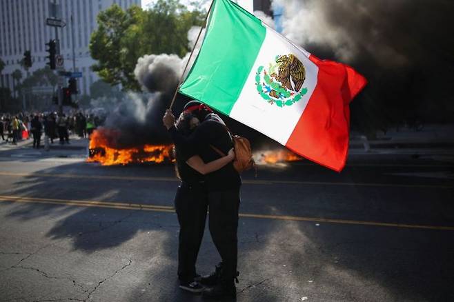미국 캘리포니아주 로스앤젤레스 도심에서 연방 이민 단속에 반대하는 시위가 열린 가운데 시위대가 멕시코 국기를 들고 있다. 로이터연합뉴스.