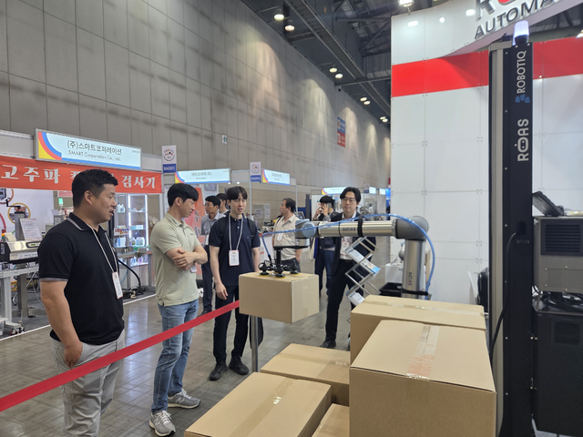 식품기기가 전시된 킨텍스 제2전시장에서 관람객들이 ‘진공 핸드’가 부착된 협동로봇을 보고 있다.