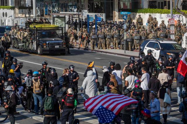 9일(현지 시간) LA 연방정부 청사 앞에서 캘리포니아 주 방위군 병력이 경계 활동이 펼치는 가운데 LA 경찰들이 강압적인 불법 이민자 단속에 항의하는 시위대와 충돌하고 있다. AFP 연합뉴스