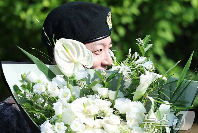 방탄소년단(BTS)의 정국이 11일 오전 경기도 연천군 연천공설운동장에서 군복무를 마친 뒤 꽃다발을 받고 수줍은 미소를 짓고 있다. ⓒ News1 권현진 기자