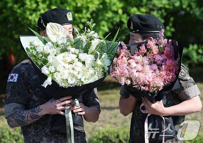 방탄소년단(BTS)의 정국과 지민(오른쪽)이 11일 오전 경기도 연천군 연천공설운동장에서 군복무를 마친 뒤 수줍은 미소를 짓고 있다. ⓒ News1 권현진 기자