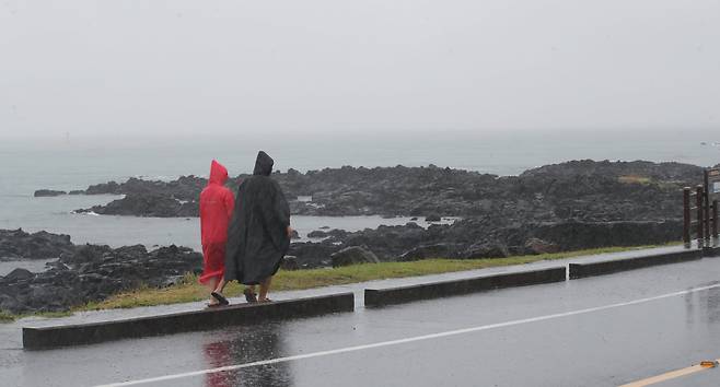 제주시 용담해안도로에서 관광객들이 우비를 입고 이동하고 있다. /뉴스1