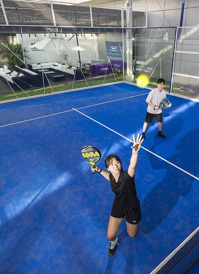서울 용산 아이파크몰에 마련된 빠델 코트에서 한 여성이 스매싱을 시도하고 있다. 경기장을 둘러싼 투명 유리벽 덕에 테니스보다 다채로운 플레이가 가능하다. /양수열 영상미디어 기자