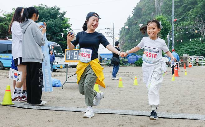 15일 경북 울릉군 울릉읍 울릉문화예술체험장에서 열린 독도지키기 제20회 울릉도 국제 마라톤대회에서 최연소 김조안 참가자(오른쪽)가 어머니와 함께 결승선을 통과하고 있다.