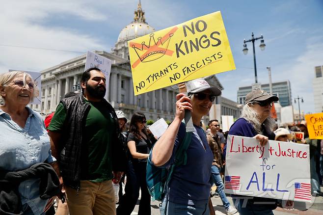 14일(현지시간) 캘리포니아주 샌프랜시스코에서 한 시민이 "미국에는 왕이 없다"는 팻말을 들고 행진하고 있다. ⓒ 로이터=뉴스1 ⓒ News1 박형기 기자